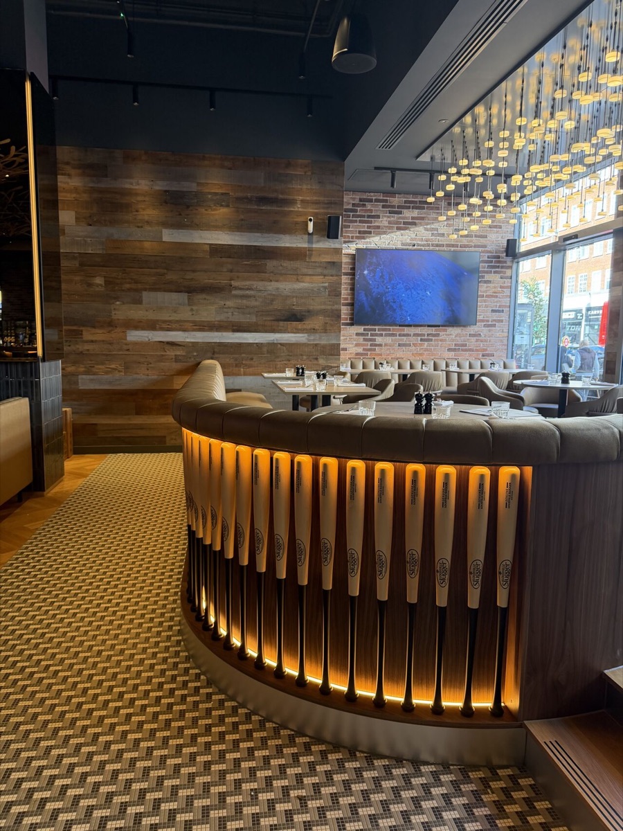 A curved banquette clad in lit baseball bats